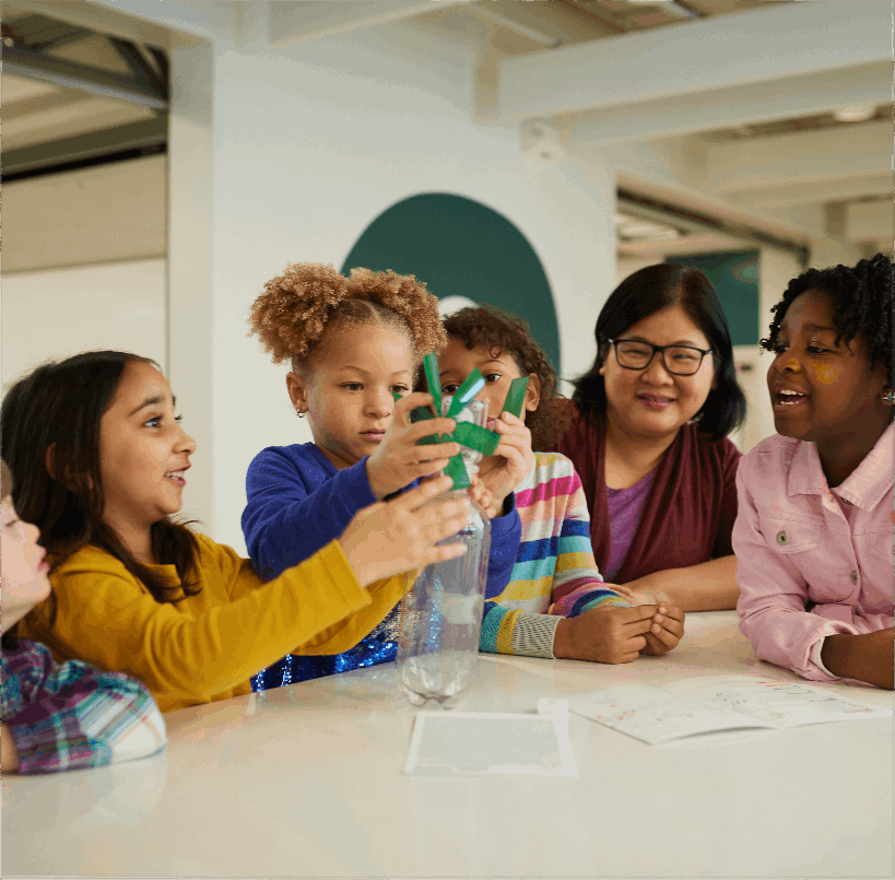 Young girls putting together model windmill out of plastic bottles