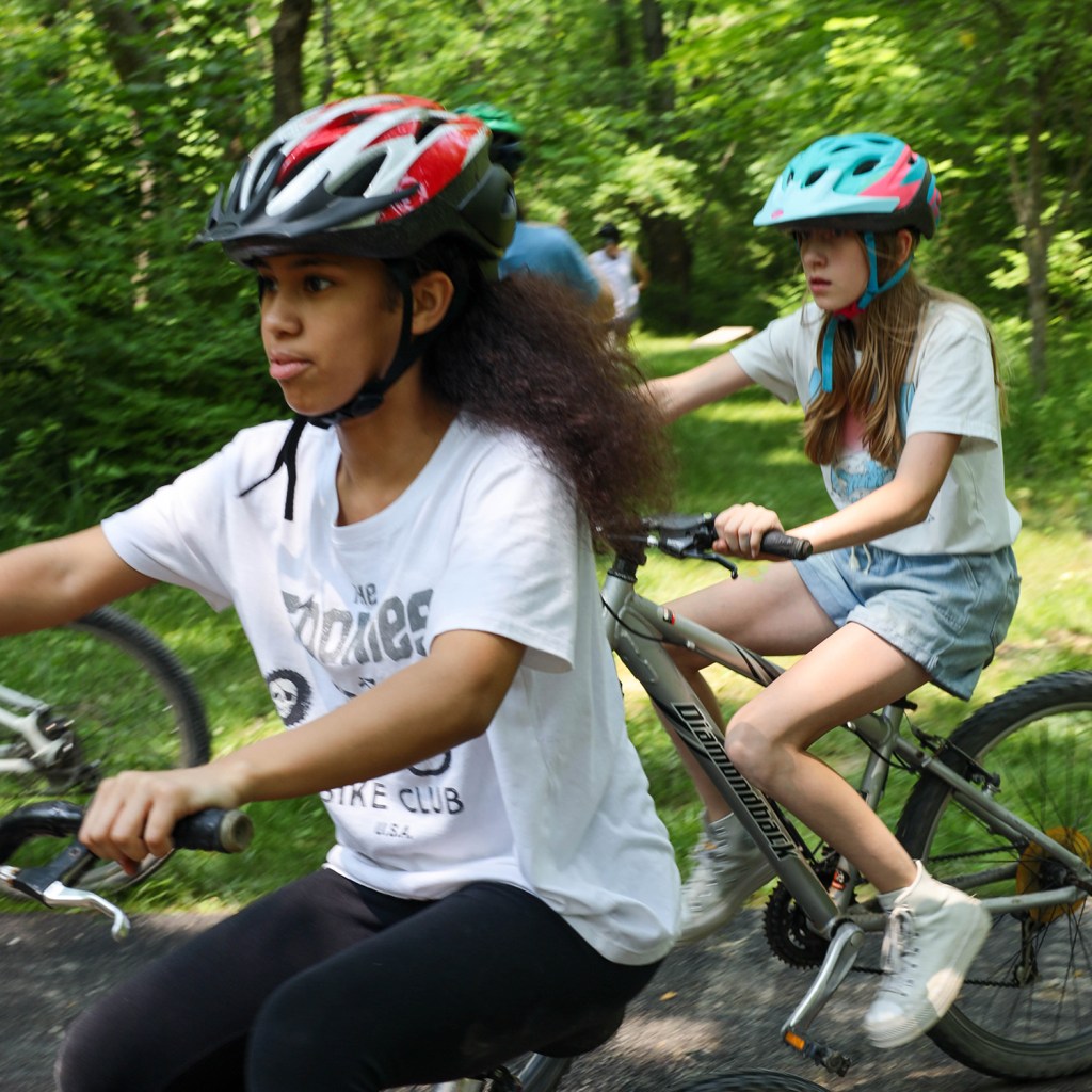 Two girls outdoors riding bikes with helmets