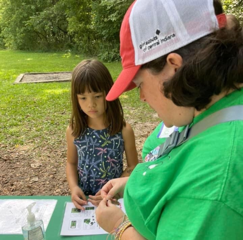 Adult volunteer helping a young Girl Scout